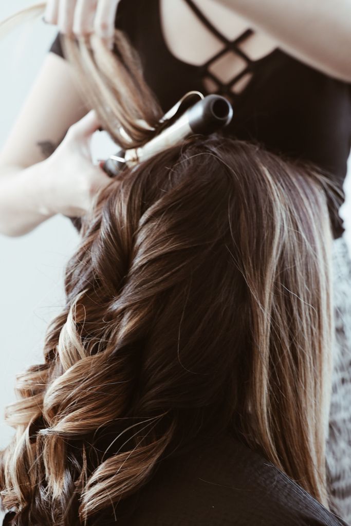 Long hair getting styled with curling iron.